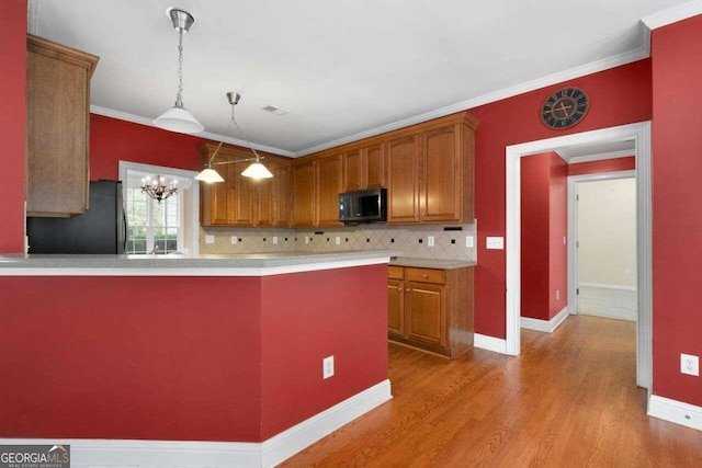 kitchen featuring ornamental molding, light wood-type flooring, kitchen peninsula, and black refrigerator