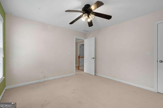 carpeted spare room featuring ceiling fan