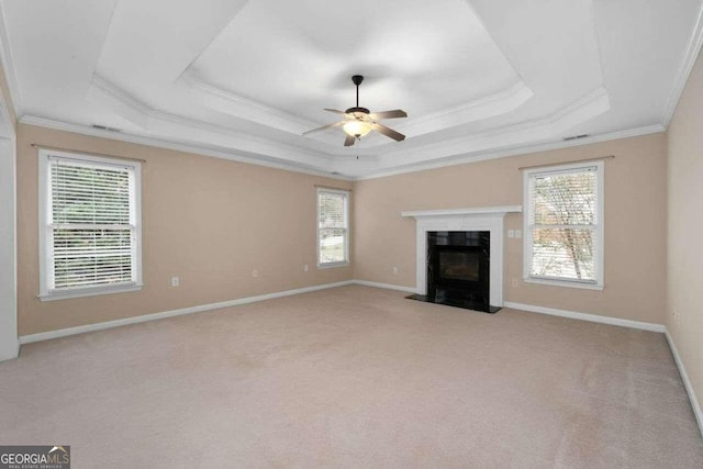 unfurnished living room featuring ornamental molding, light carpet, ceiling fan, and a raised ceiling