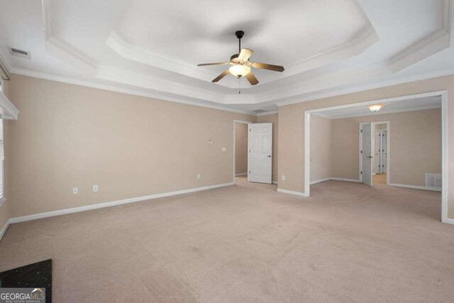 empty room with ornamental molding, ceiling fan, and a raised ceiling