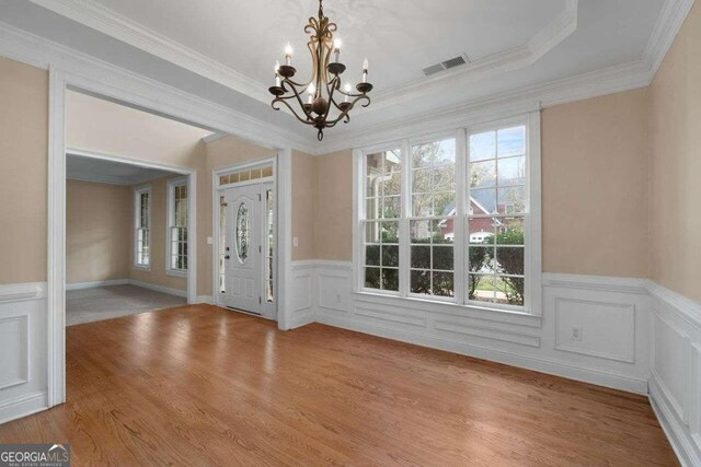 foyer entrance featuring light hardwood / wood-style flooring, a notable chandelier, and crown molding