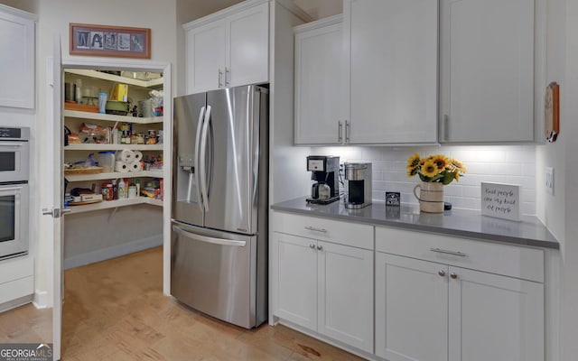 kitchen featuring light hardwood / wood-style flooring, decorative backsplash, stainless steel fridge, and white cabinets