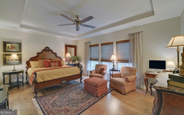 bedroom featuring light wood-type flooring, ceiling fan, and a tray ceiling