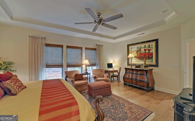 bedroom with light hardwood / wood-style floors, ceiling fan, and a tray ceiling