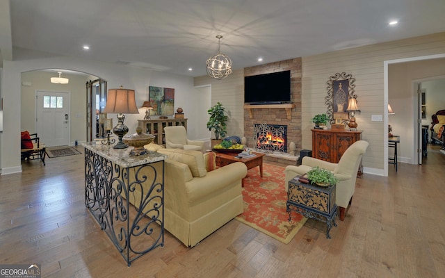 living room with a fireplace, light hardwood / wood-style floors, and an inviting chandelier