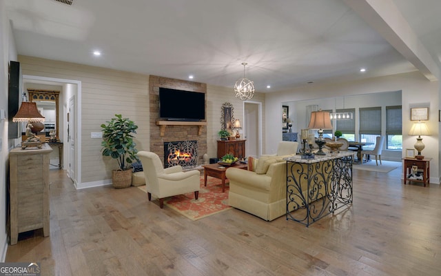 living room featuring light wood-type flooring, a fireplace, and an inviting chandelier