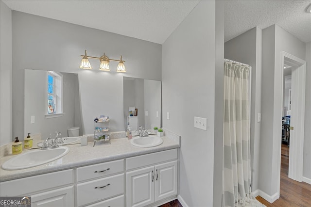 bathroom featuring curtained shower, hardwood / wood-style floors, vanity, toilet, and a textured ceiling