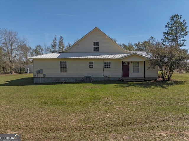 rear view of house featuring central air condition unit and a lawn