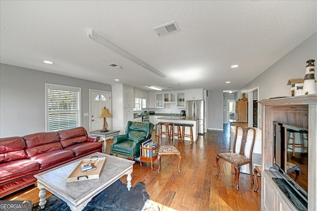 living room featuring light wood-type flooring and a textured ceiling