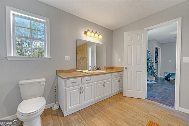 bathroom with lofted ceiling, vanity, toilet, a textured ceiling, and wood-type flooring