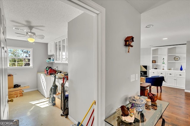 kitchen with a textured ceiling, ceiling fan, washer / dryer, light hardwood / wood-style floors, and white cabinetry