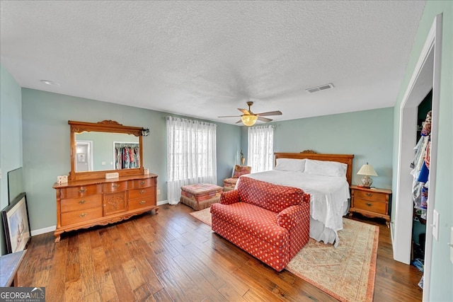 bedroom featuring ceiling fan, hardwood / wood-style flooring, and a textured ceiling