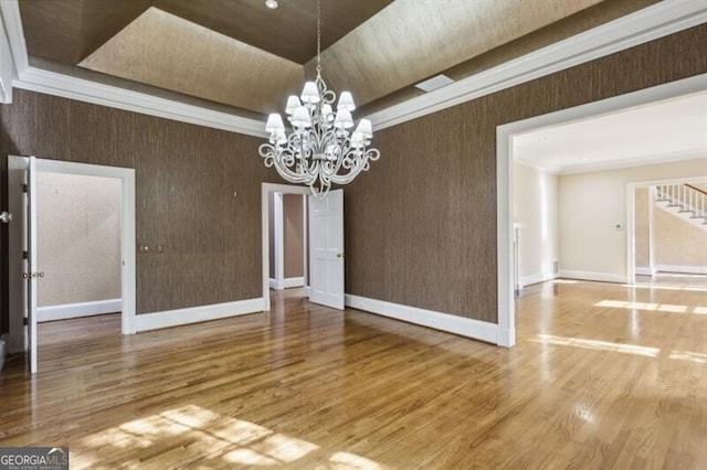 unfurnished dining area featuring a notable chandelier, wood-type flooring, and crown molding