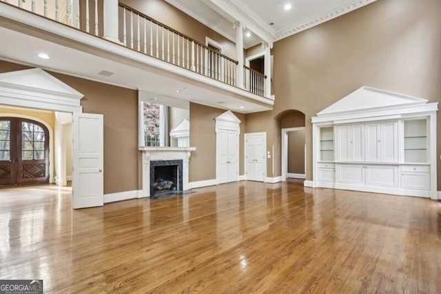 unfurnished living room featuring a fireplace, a high ceiling, french doors, and hardwood / wood-style floors