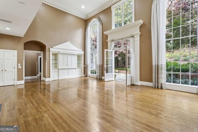 interior space featuring hardwood / wood-style flooring, a towering ceiling, and crown molding