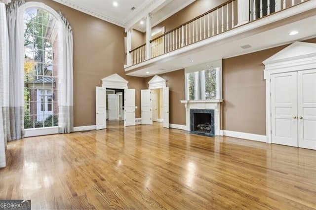 unfurnished living room featuring plenty of natural light, wood-type flooring, and a high ceiling