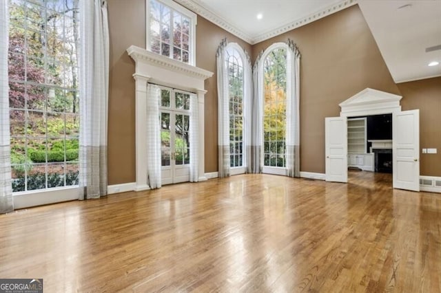 interior space with hardwood / wood-style floors, a towering ceiling, and crown molding