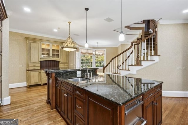 kitchen with sink, hanging light fixtures, a center island with sink, and light hardwood / wood-style floors