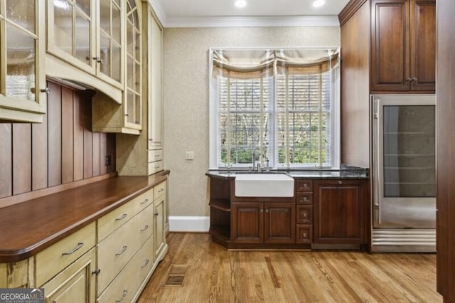 kitchen featuring ornamental molding, sink, cream cabinets, light hardwood / wood-style flooring, and wine cooler