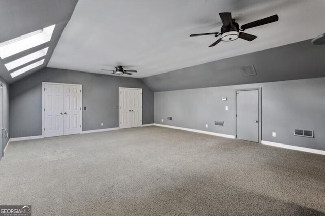 additional living space with carpet flooring, ceiling fan, and vaulted ceiling with skylight