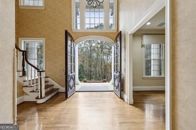 entrance foyer with light hardwood / wood-style flooring, a high ceiling, and an inviting chandelier