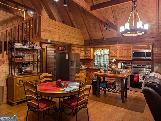 living room featuring an inviting chandelier, a healthy amount of sunlight, light wood-type flooring, and a wood stove