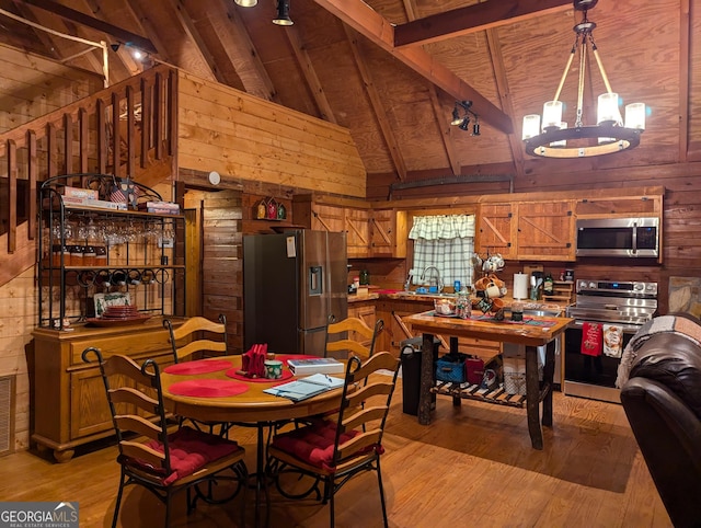 dining area featuring high vaulted ceiling, wood walls, beamed ceiling, a chandelier, and light wood-type flooring