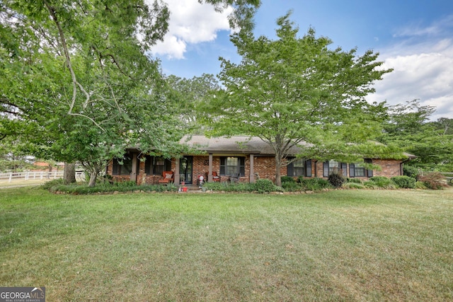 view of front of home with a front yard, brick siding, and fence