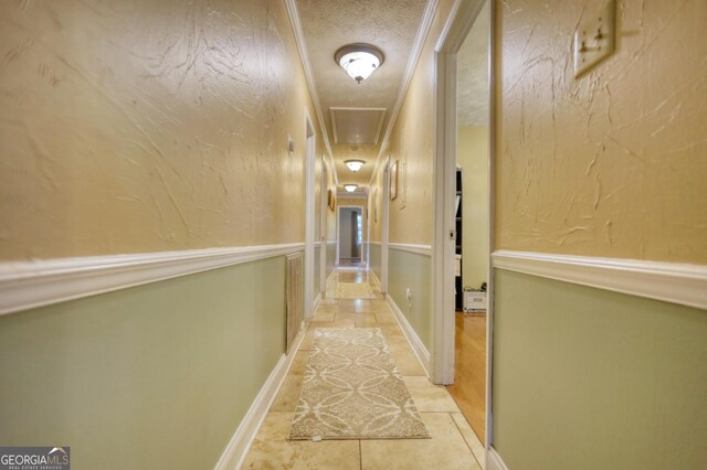 corridor with ornamental molding and a textured ceiling