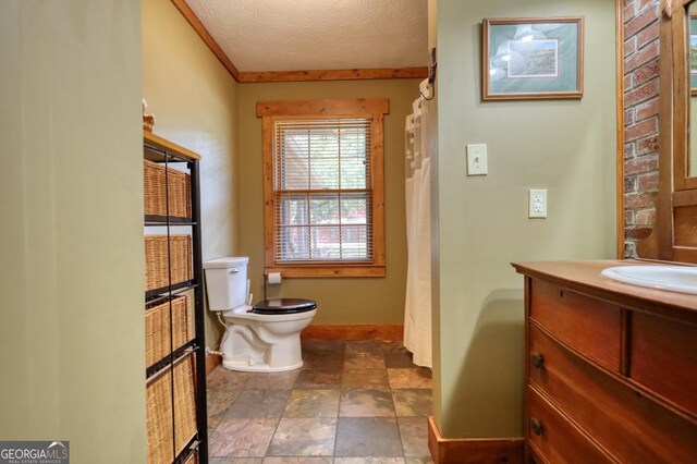 bathroom with vanity, ornamental molding, a textured ceiling, and toilet