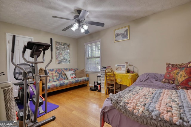 bedroom with light wood-type flooring, ceiling fan, and a textured ceiling