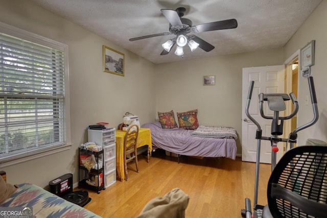 bedroom with hardwood / wood-style floors, a textured ceiling, and ceiling fan