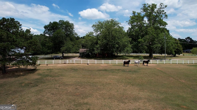 view of home's community with a yard, a rural view, and fence