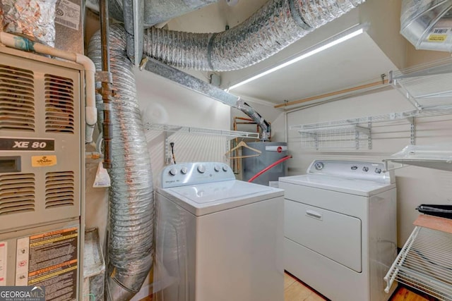 laundry room with heating unit, washing machine and dryer, and water heater