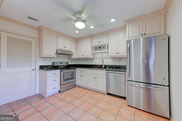 kitchen featuring sink, light tile patterned floors, crown molding, appliances with stainless steel finishes, and dark stone counters