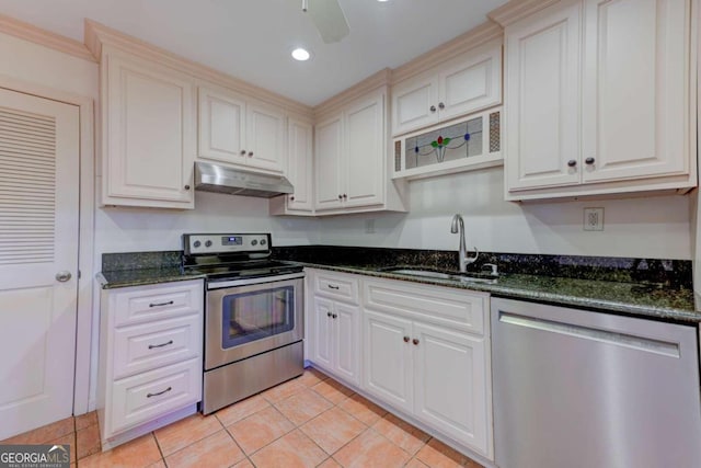 kitchen featuring light tile patterned floors, sink, appliances with stainless steel finishes, dark stone countertops, and white cabinetry