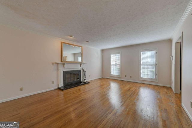 unfurnished living room featuring light hardwood / wood-style flooring, ornamental molding, and a textured ceiling