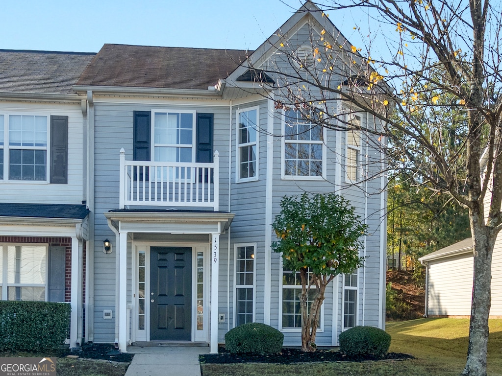 view of property featuring a balcony and a front yard