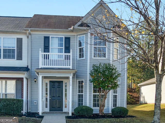 view of property featuring a balcony and a front yard