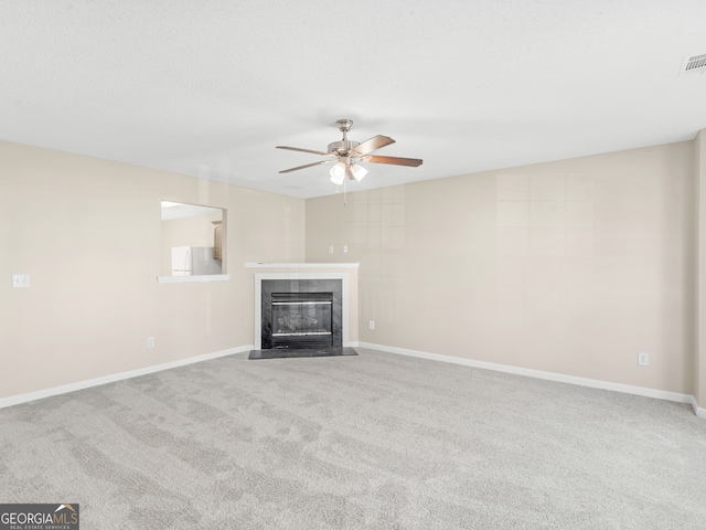 unfurnished living room featuring ceiling fan, a fireplace, and light colored carpet