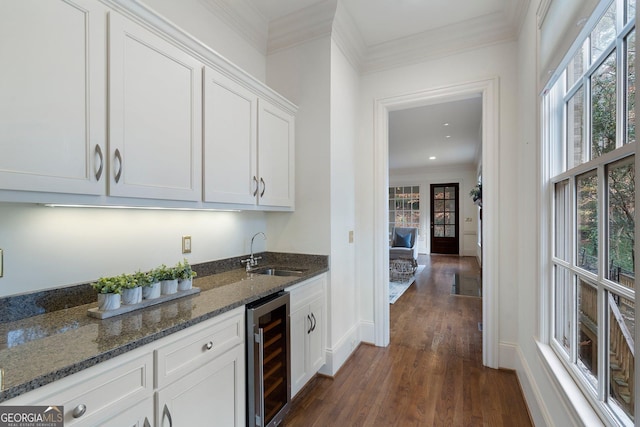 kitchen featuring sink, a healthy amount of sunlight, wine cooler, dark stone countertops, and white cabinets