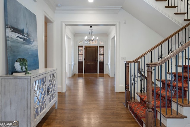 entrance foyer with ornamental molding, dark hardwood / wood-style floors, and an inviting chandelier