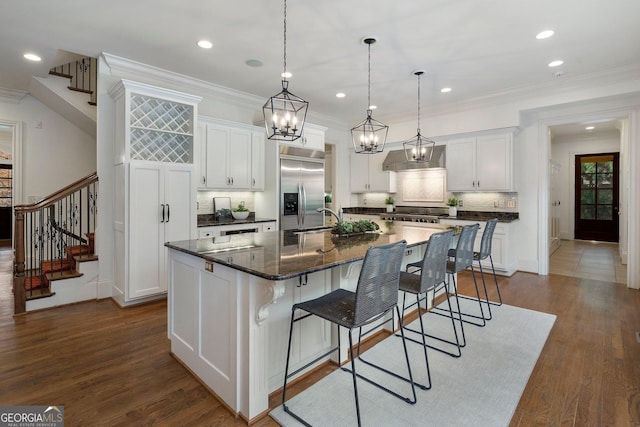 kitchen with decorative backsplash, a kitchen bar, stainless steel appliances, white cabinets, and a large island