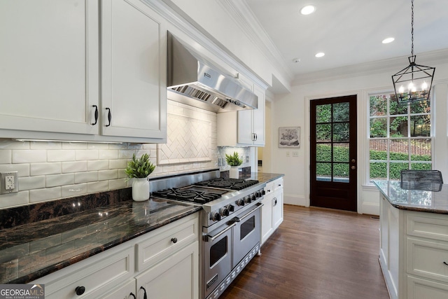 kitchen with white cabinets, wall chimney exhaust hood, range with two ovens, and dark stone counters