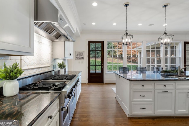 kitchen featuring white cabinetry, range with two ovens, dark stone countertops, and wall chimney range hood