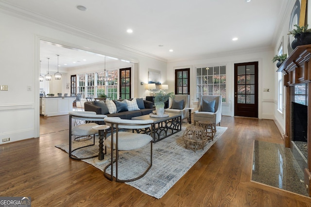 living room featuring crown molding, dark hardwood / wood-style flooring, a high end fireplace, and an inviting chandelier