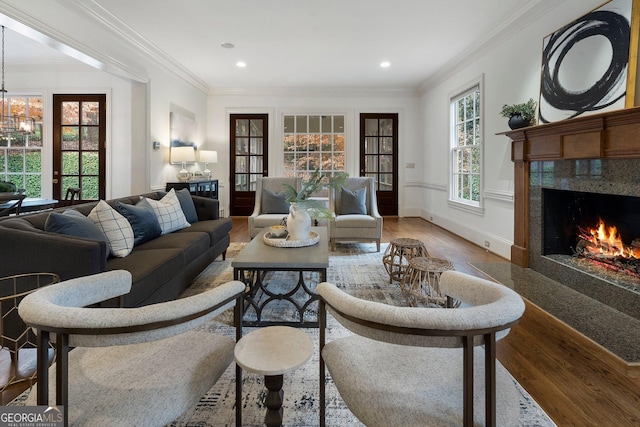 living room with french doors, a high end fireplace, crown molding, hardwood / wood-style floors, and a chandelier