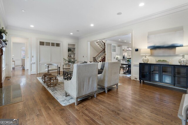 living room featuring dark hardwood / wood-style flooring, built in features, and crown molding