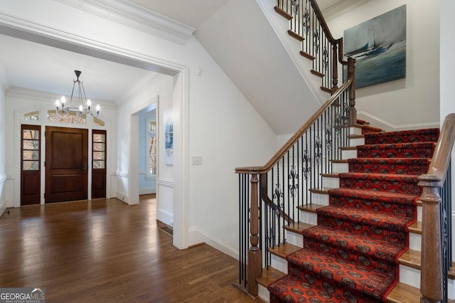 foyer entrance with a chandelier, crown molding, and dark wood-type flooring