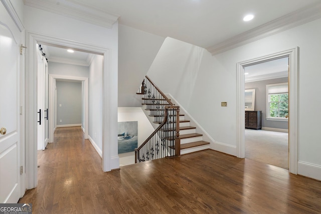 interior space featuring a barn door, hardwood / wood-style flooring, and ornamental molding